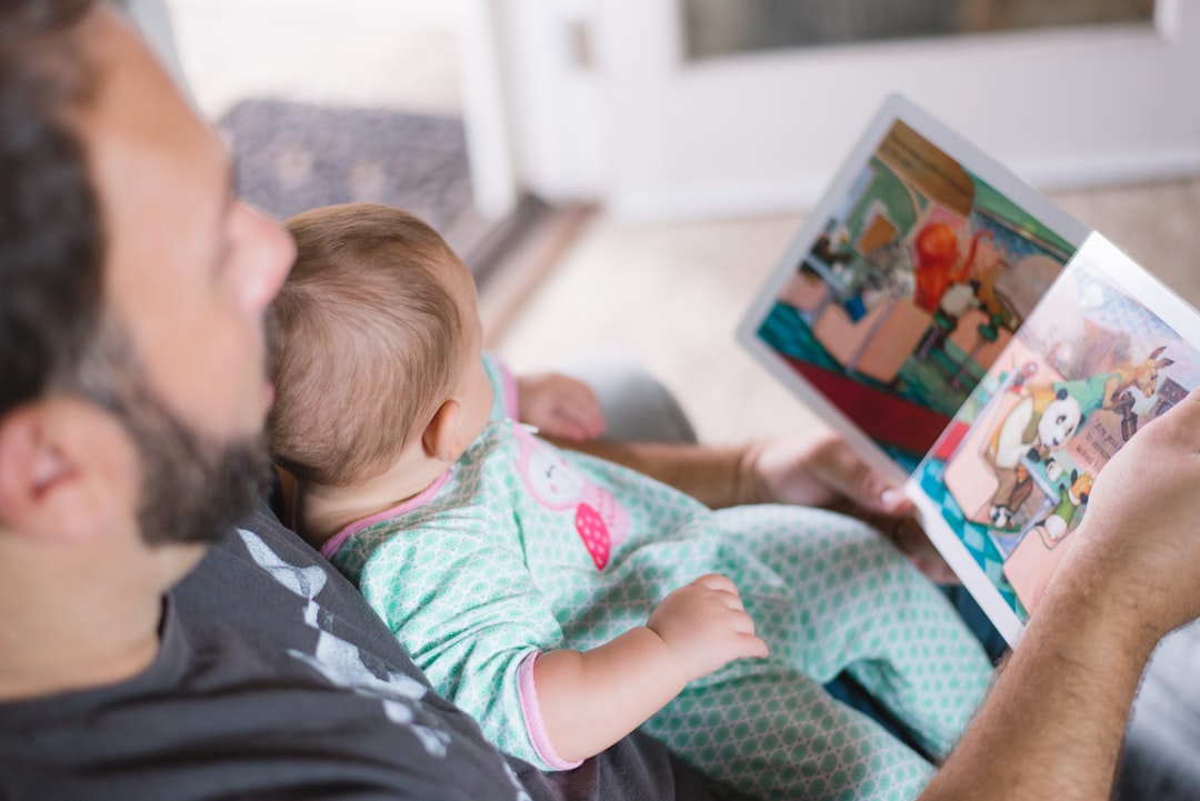 Photo by Picsea person carrying baby while reading book